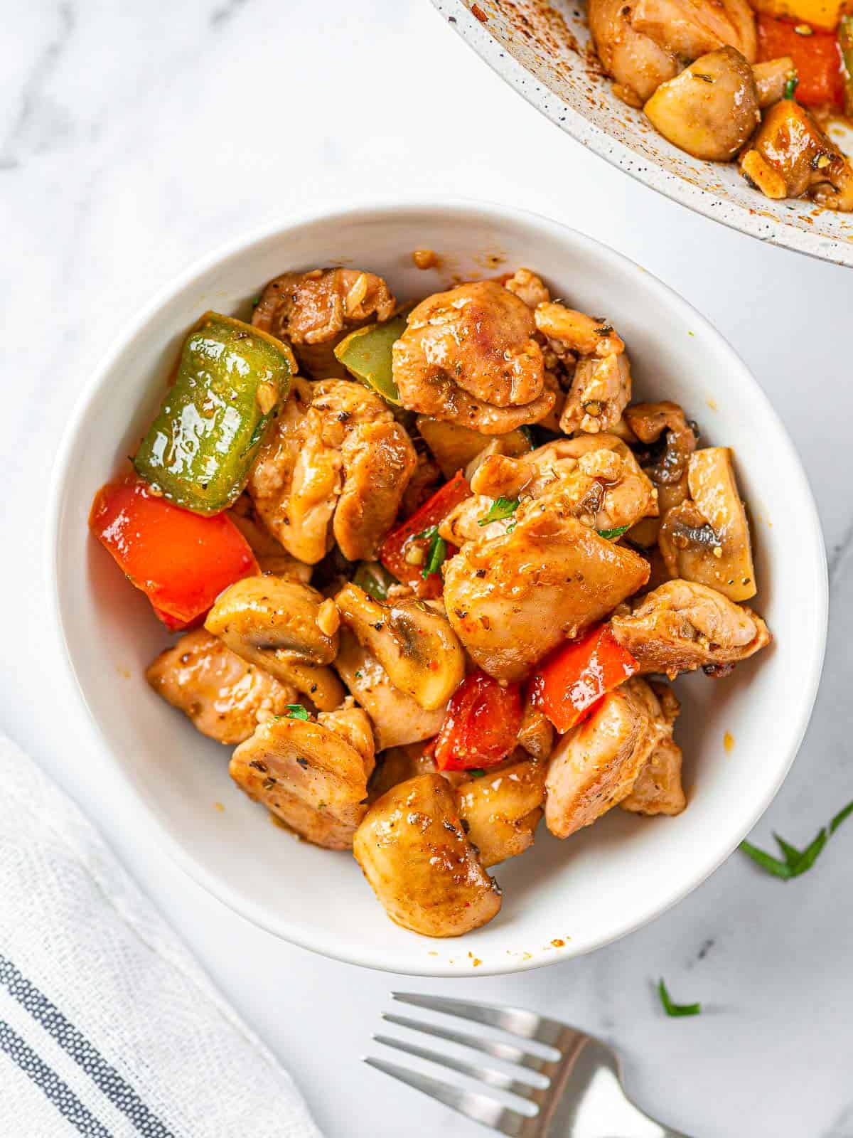 Garlic butter chicken bites with mushrooms and bell peppers in a bowl.