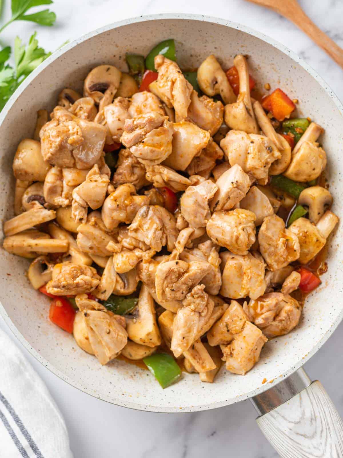 Cooked chicken returned to the skillet with mushrooms and bell peppers.
