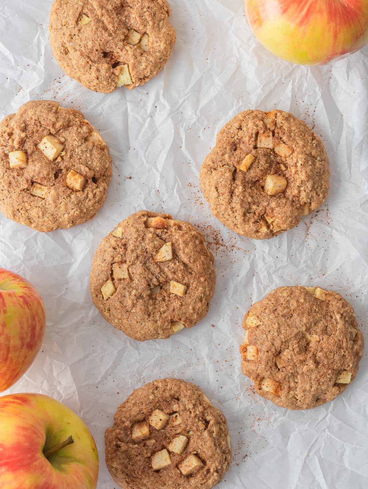 Multiple healthy apple pie oatmeal cookies on parchment paper.