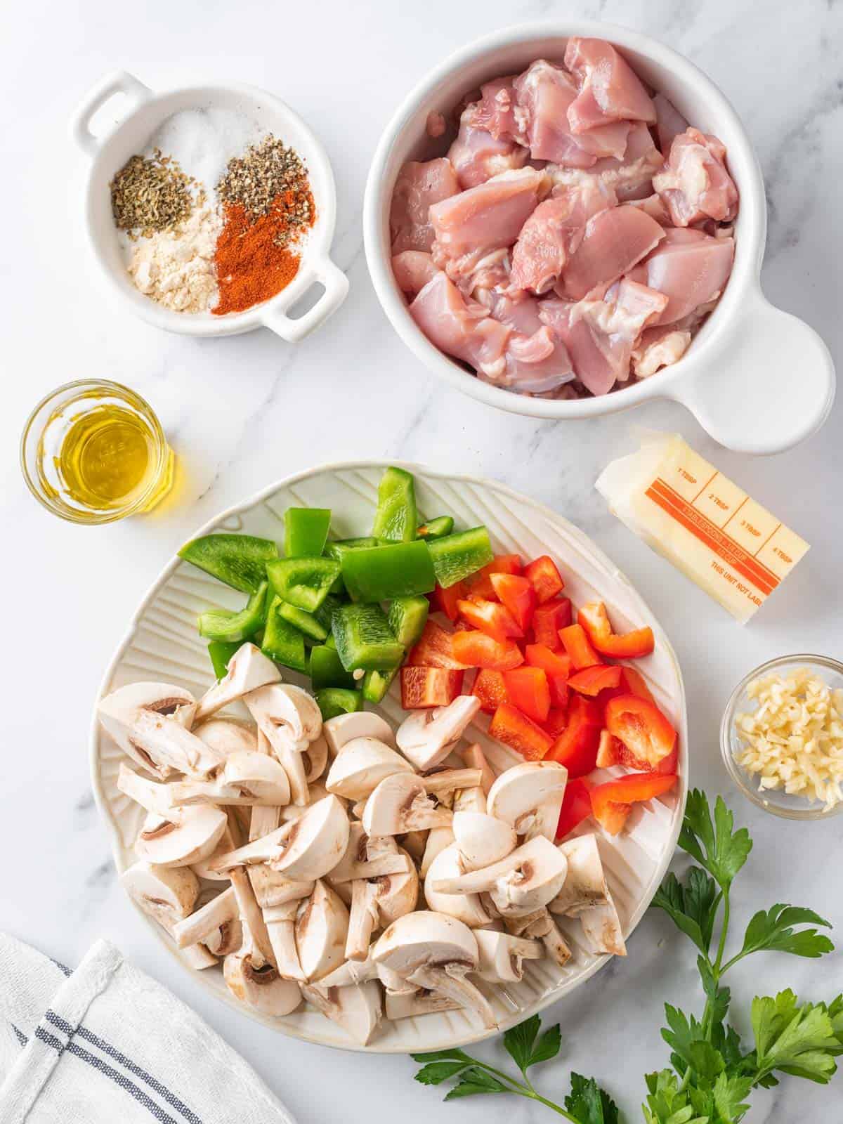 Chicken thighs, mushrooms, bell peppers, garlic, butter, oil, and seasonings.