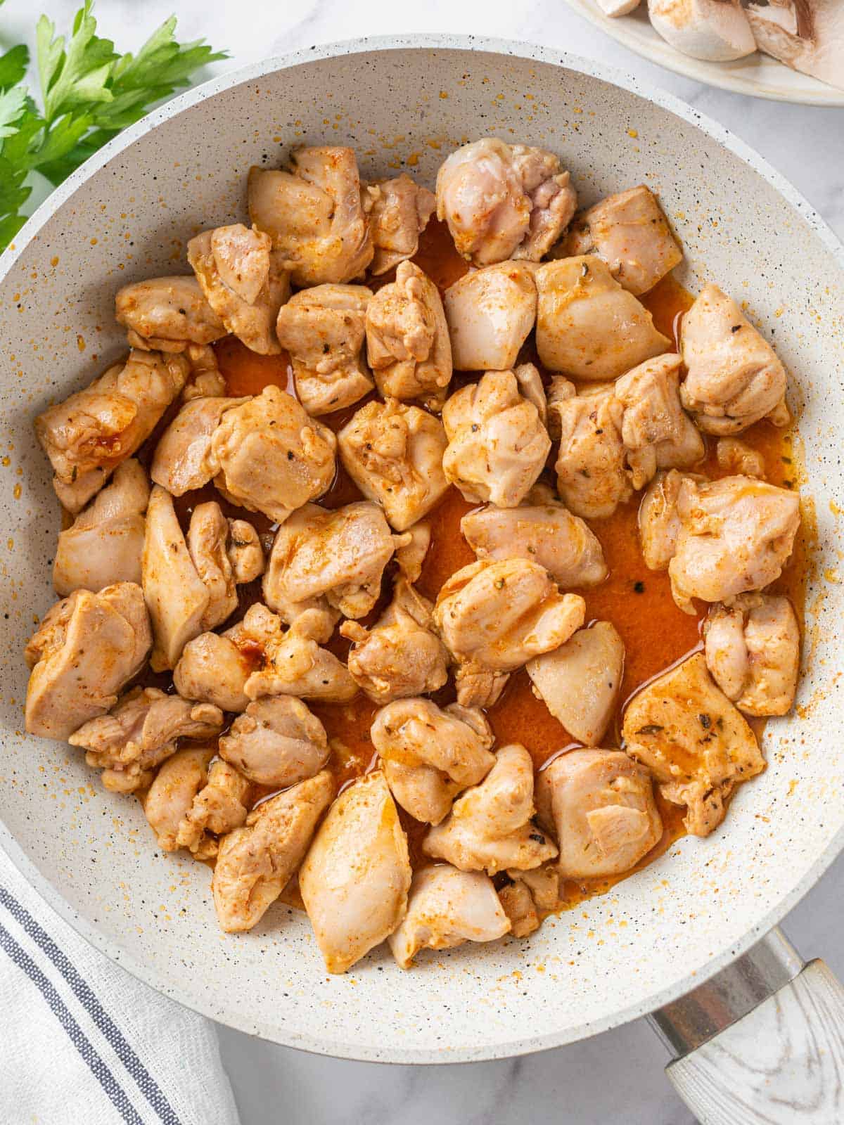Seasoned chicken pieces cooking in a skillet before the vegetables are added.