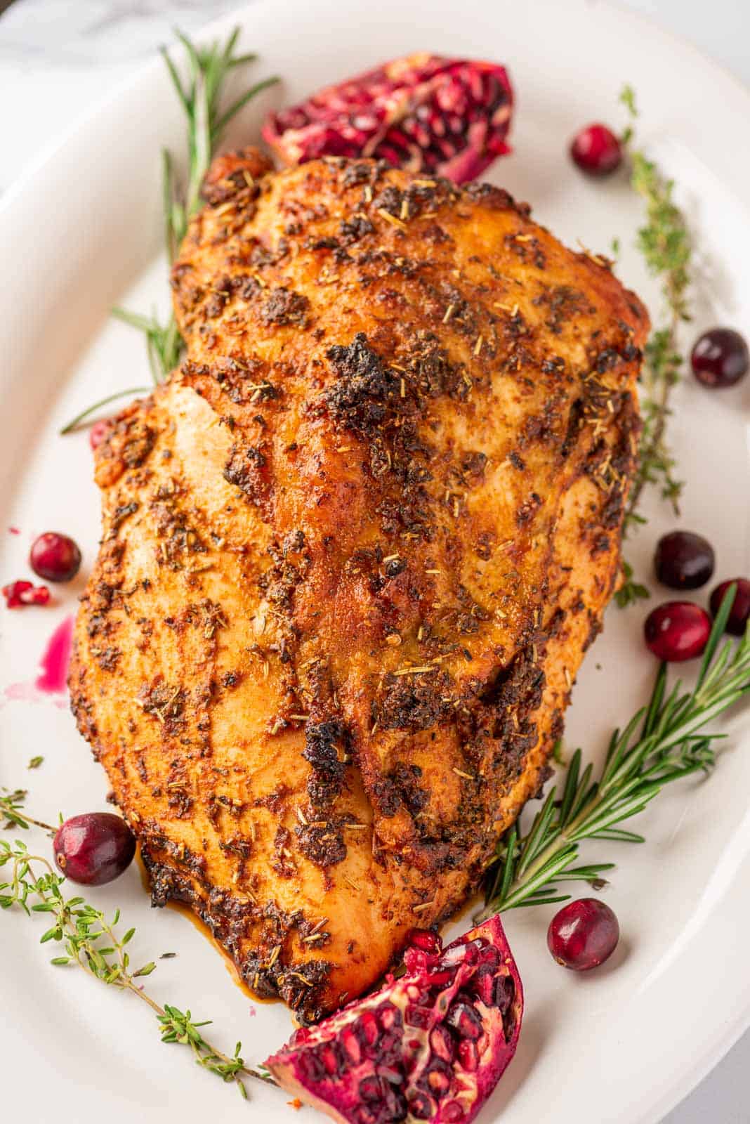 whole roasted turkey breast on a white platter, garnish with whole cranberries