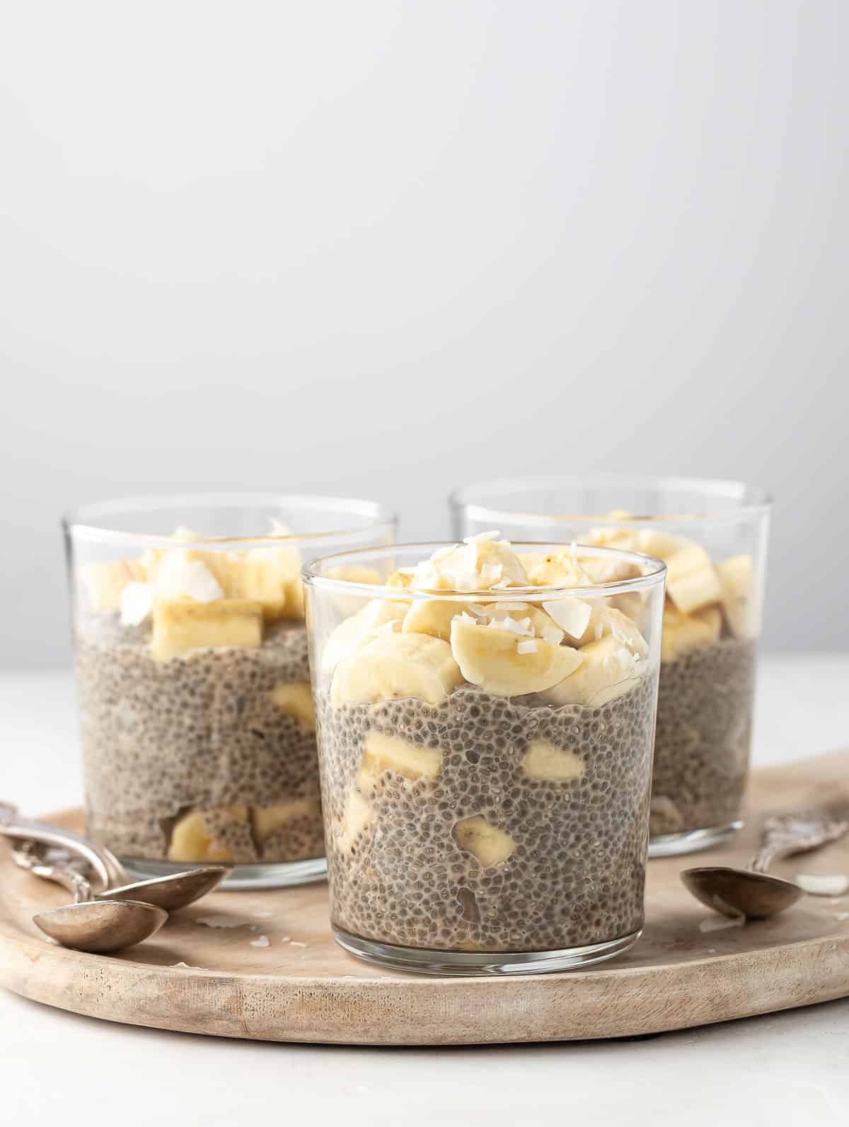 3 cups of banana chia pudding displayed on a wooden bowl