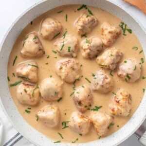 Swedish chicken meatballs in creamy gravy garnished with fresh parsley.