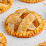 Close-up of an individual apple pie with a golden lattice crust and coarse sugar.