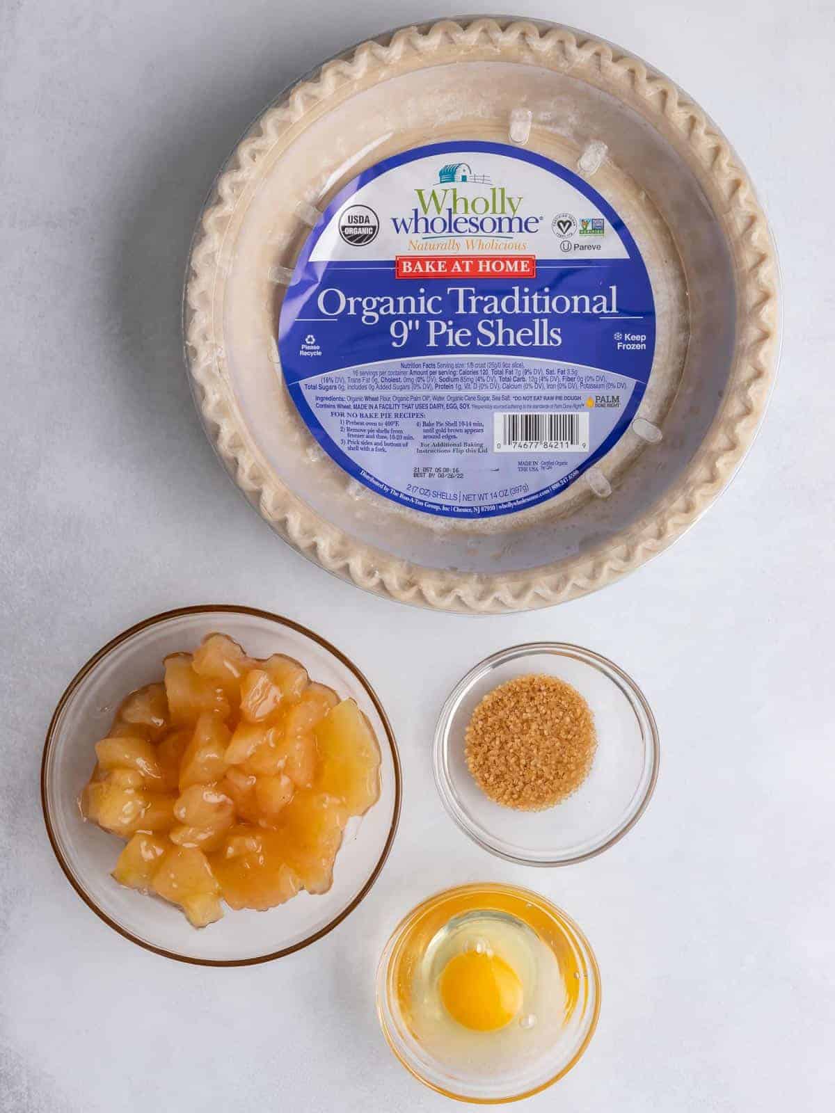 Pie crust, apple filling, egg, and coarse sugar for individual apple pies.
