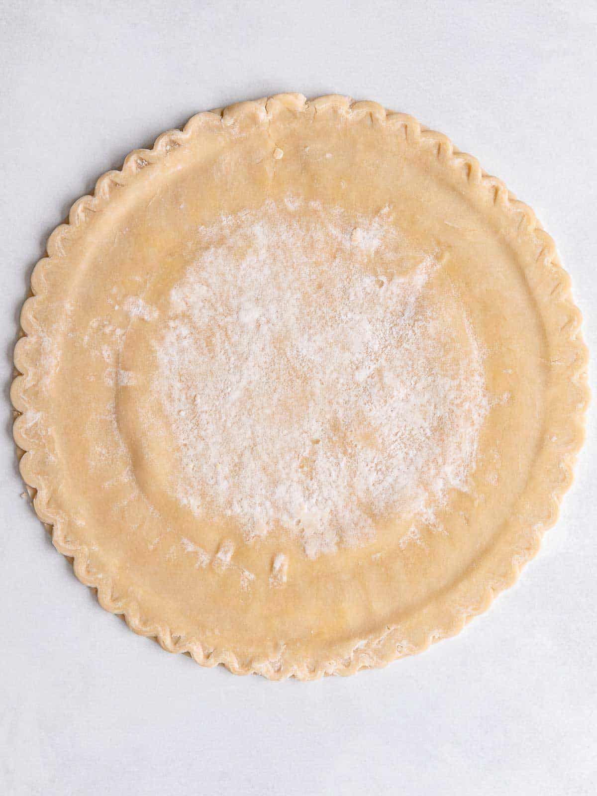 Uncooked pie crust laid flat on a lightly floured work surface.