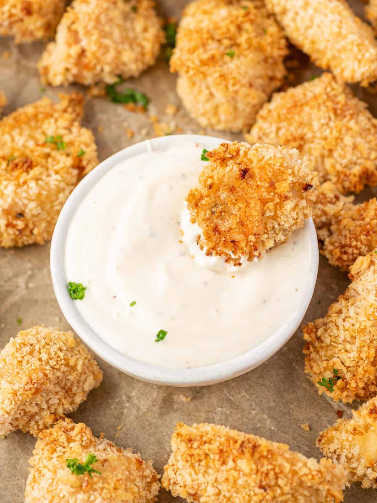 A popcorn chicken dunked in dip.