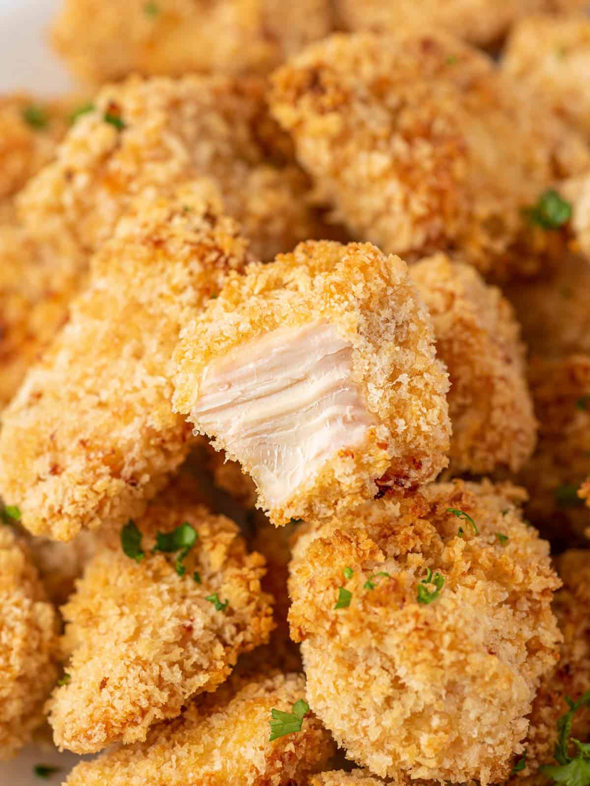 A pile of popcorn chicken with a bite taken out of one.