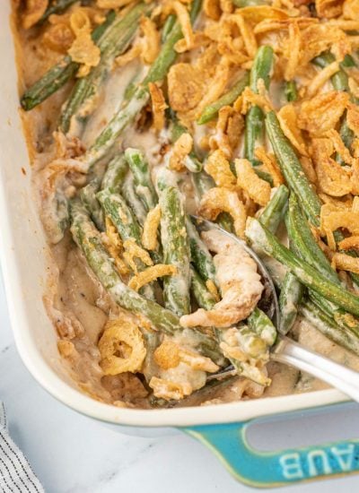 Cheesy Green Bean Casserole in a baking dish with spoon in it
