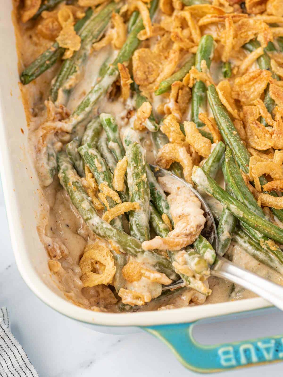 Cheesy Green Bean Casserole in a baking dish with spoon in it