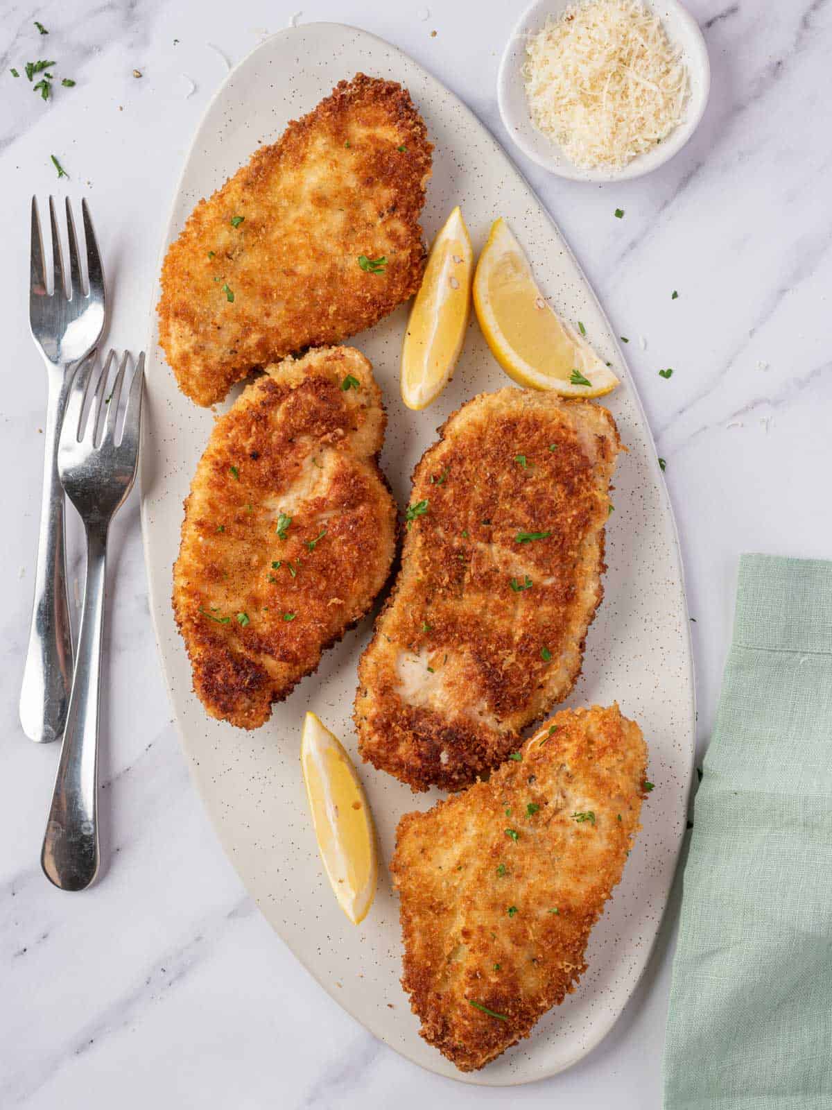 A platter of four parmesan crusted chicken breasts.