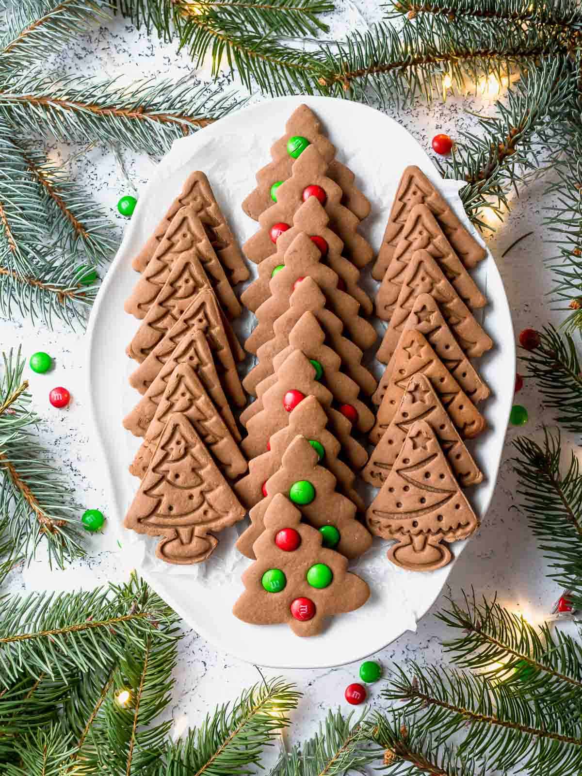 christmas tree gingerbread cookies in a white plate with decoration around
