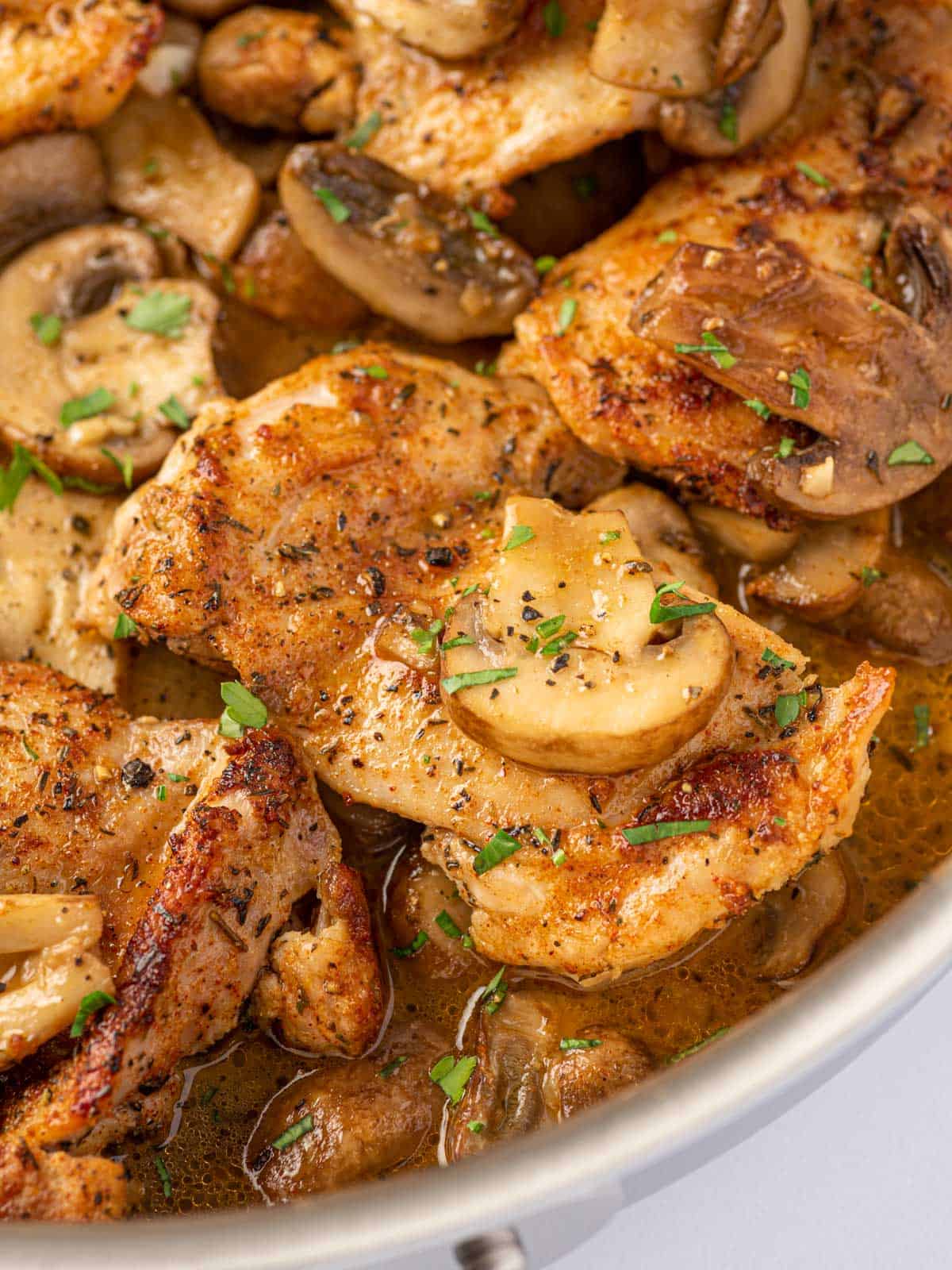 A pan of chicken thighs with garlic mushrooms.