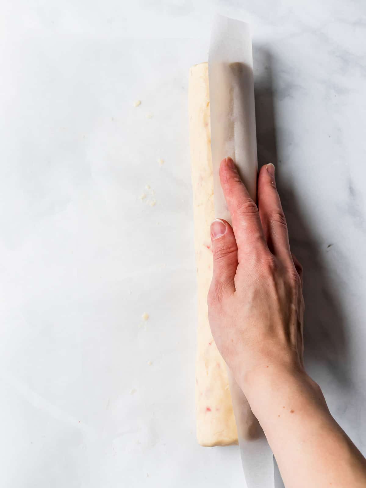 hand rolling the dough in parchment paper