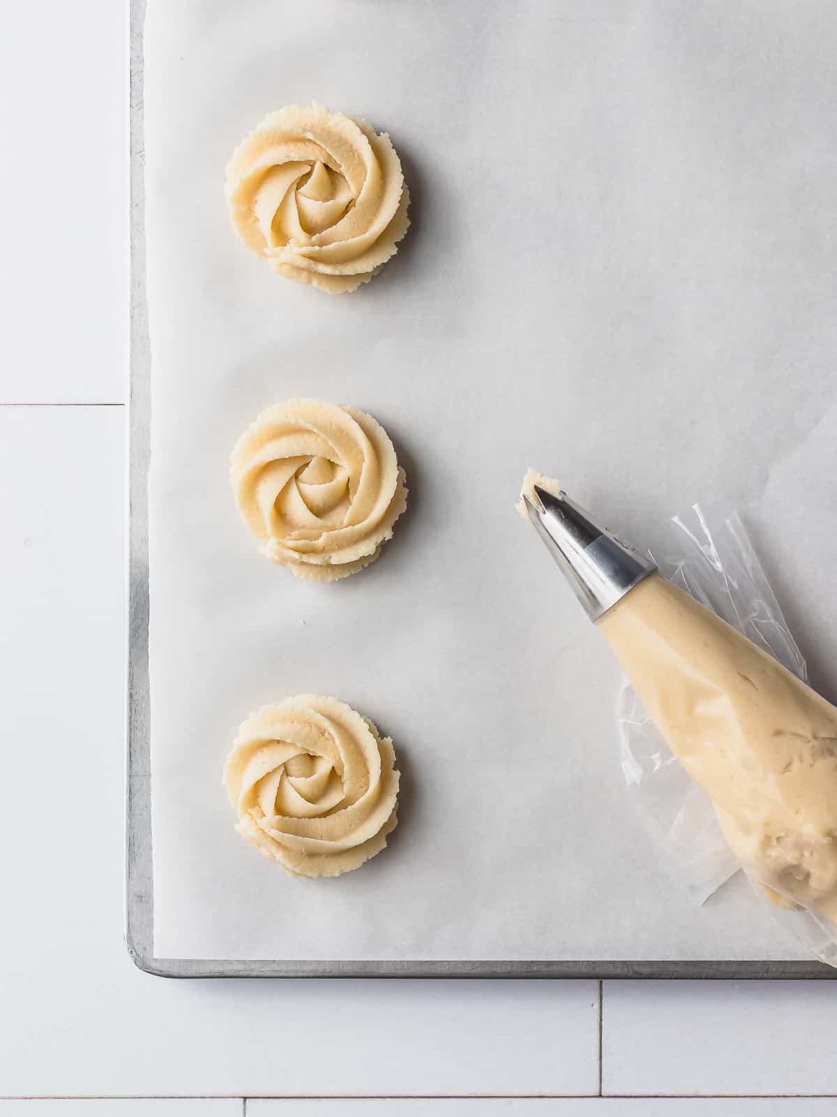 danish cookies being piped on a baking pan