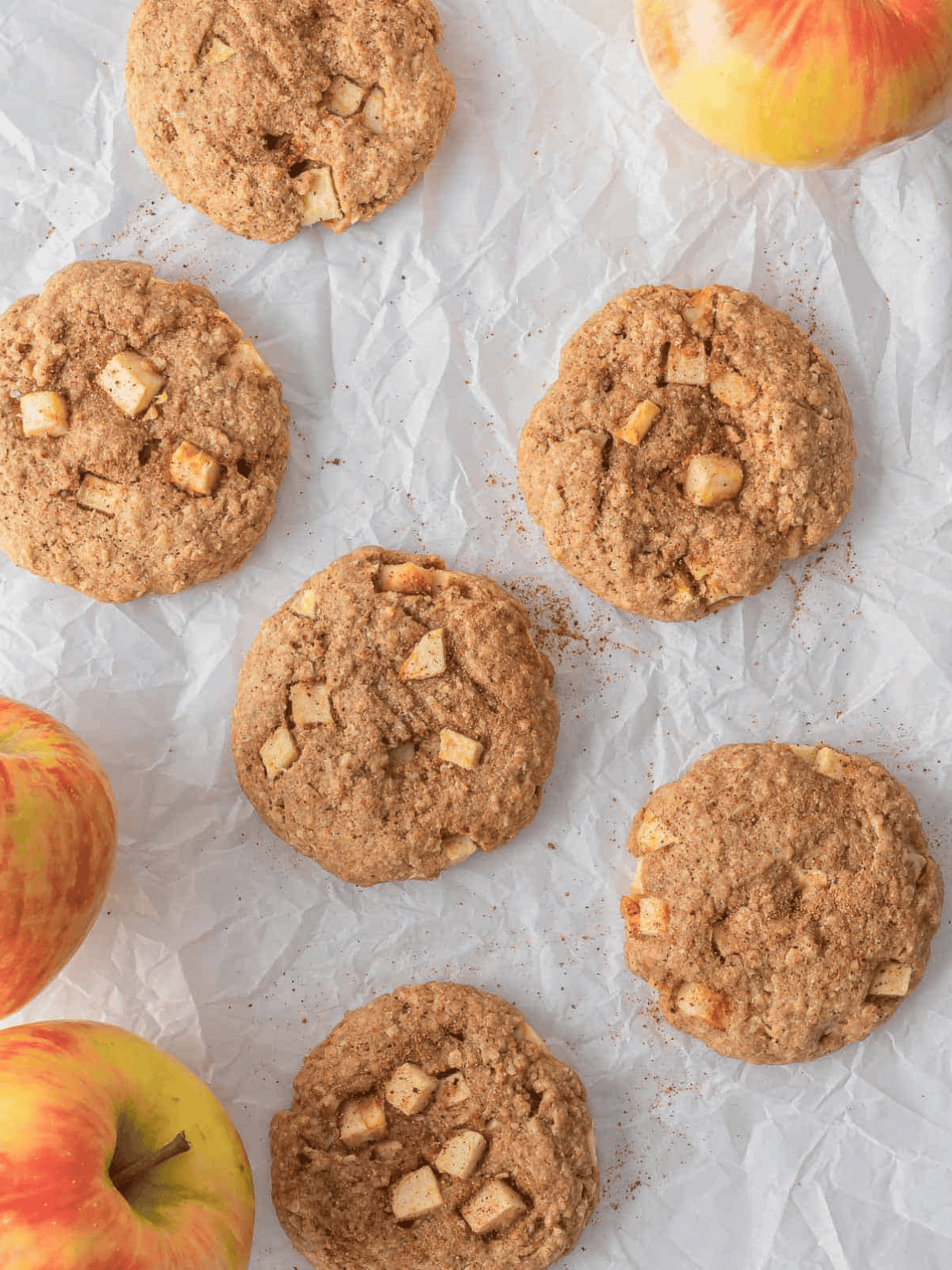 Apple cinnamon oatmeal cookies arranged with fresh apples.