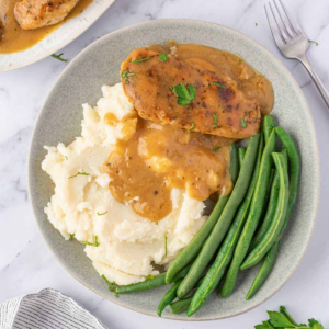 Chicken and gravy served with creamy mashed potatoes and green beans.