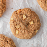 Cinnamon apple cookie with diced apples and oats on parchment paper.