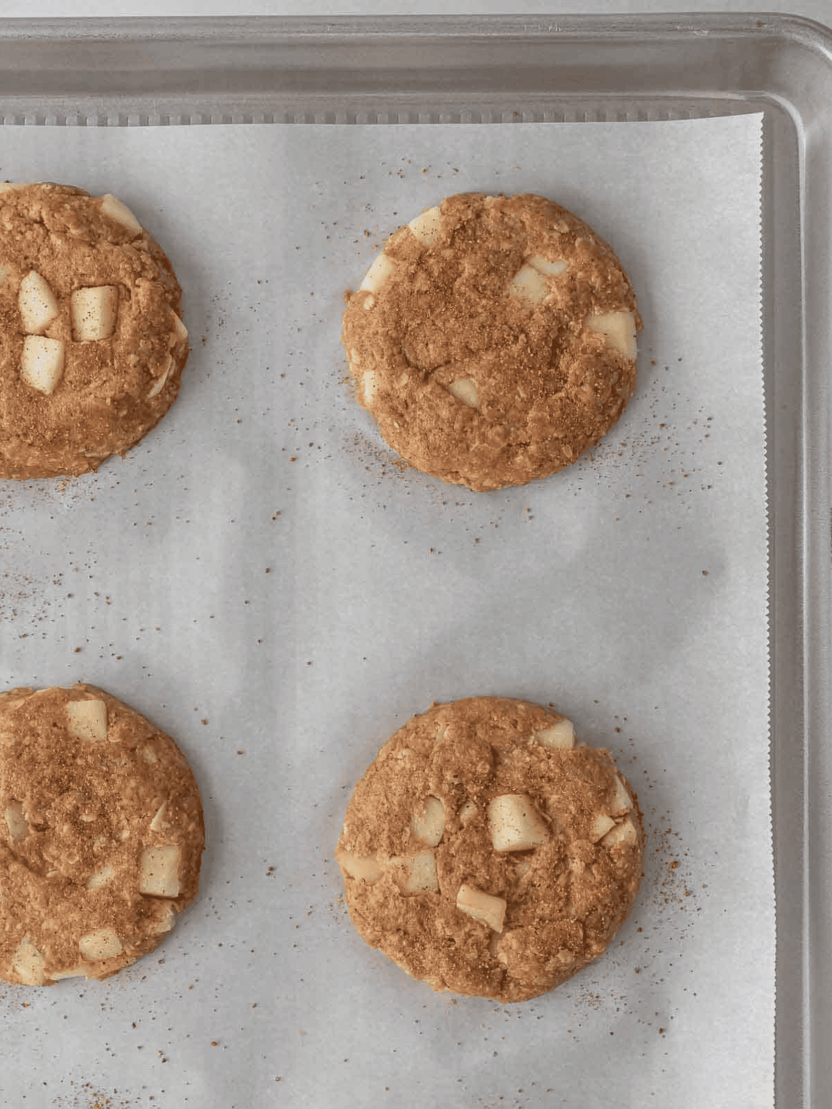 Baked apple cookies cooling on a parchment-lined baking sheet.