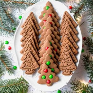 Rows of spiced tree cookies with M&M decorations arranged on a holiday platter.
