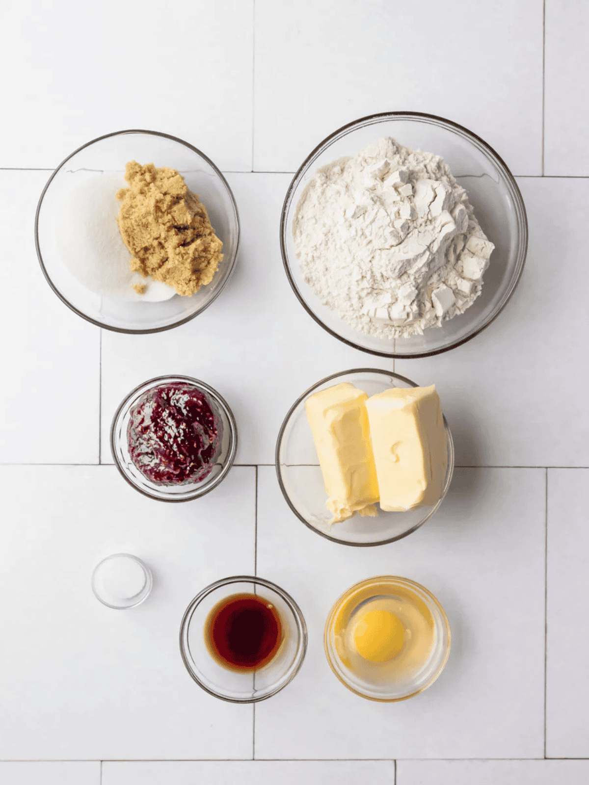 Flour, butter, sugars, raspberry jam, vanilla, egg, and salt arranged in separate bowls.