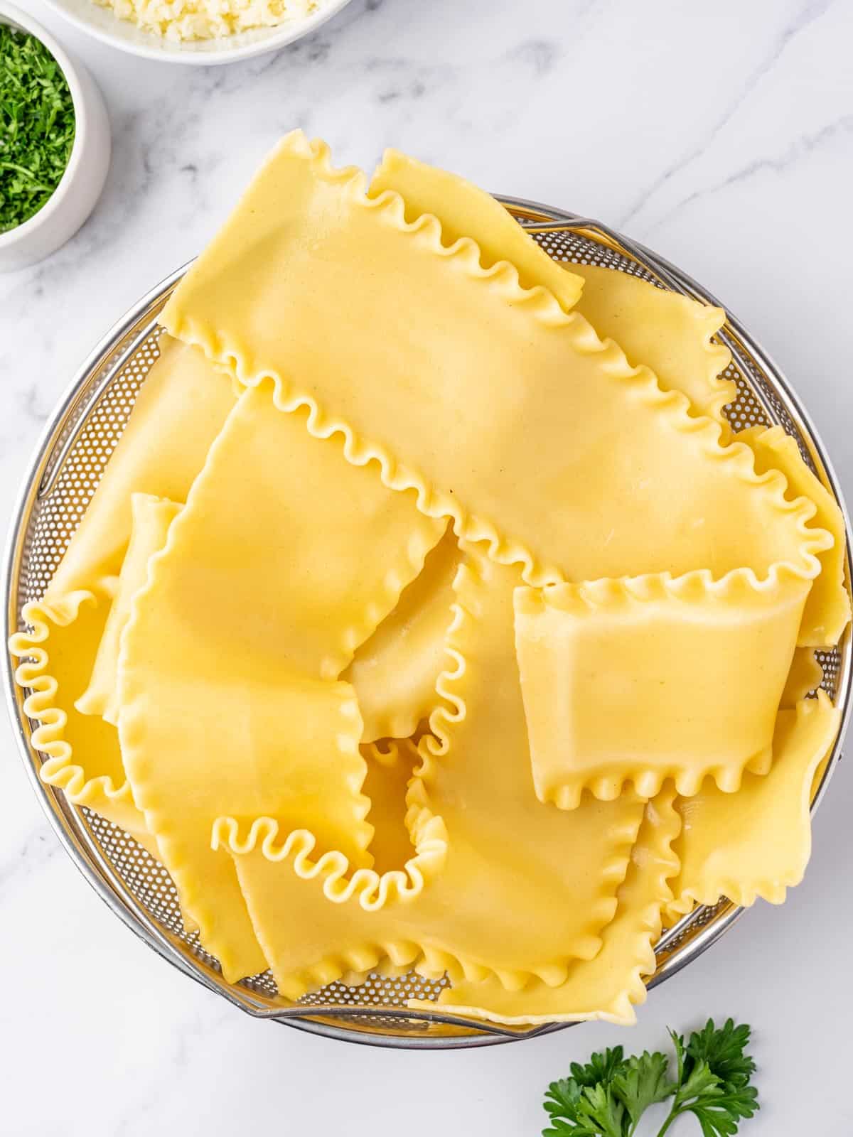 A bowl of cooked lasagna noodles for preparing alfredo roll ups.