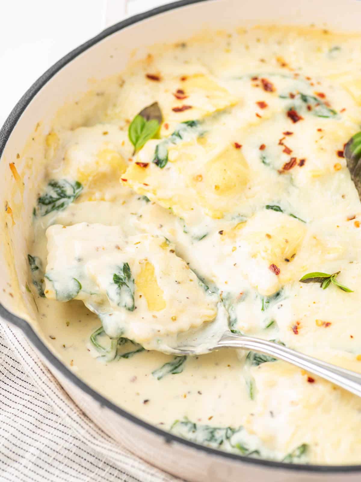 A spoon picking up a helping of ravioli with spinach.