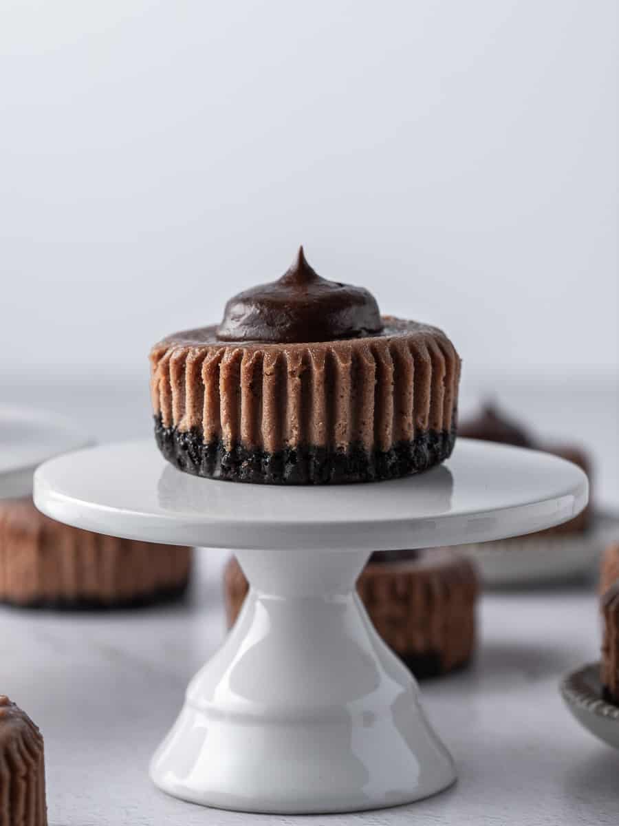 one mini chocolate cheesecake on a white cake stand