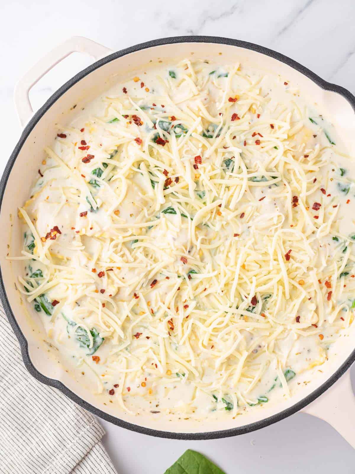 Ravioli with spinach sprinkled with cheese before baking.