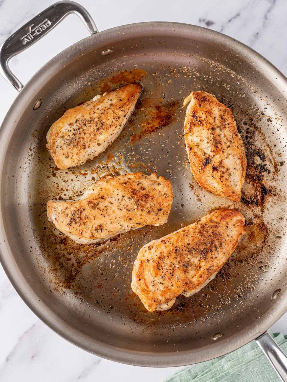 Overhead view of chicken seared in a pan.
