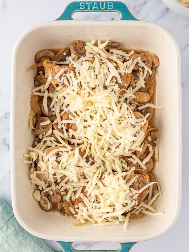 Shredded cheese added on top of chicken and mushrooms.