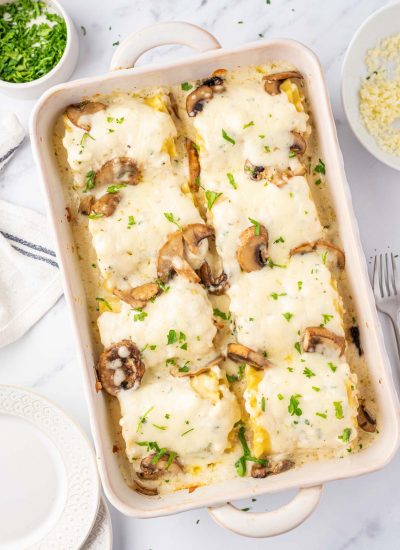 8 chicken alfredo lasagna rolls in a casserole dish with melted cheese on top.