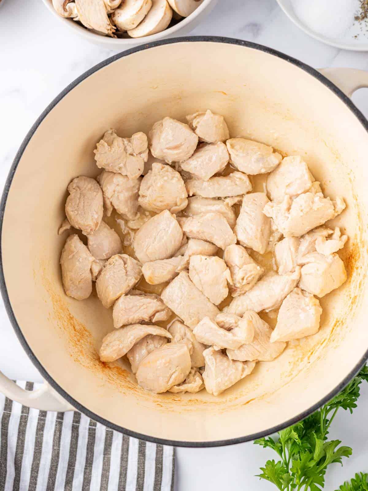 Cubed chicken cooked in a dutch oven.