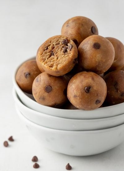 cookie dough balls in a white bowl with one bite taken out of one