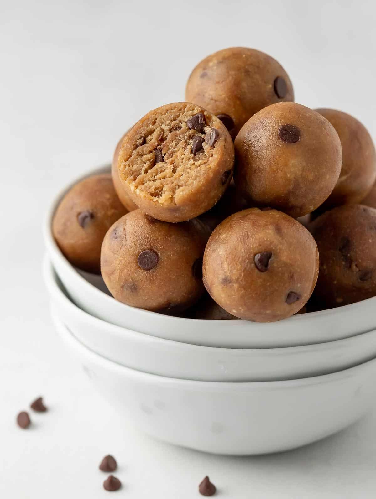 cookie dough balls in a white bowl with one bite taken out of one