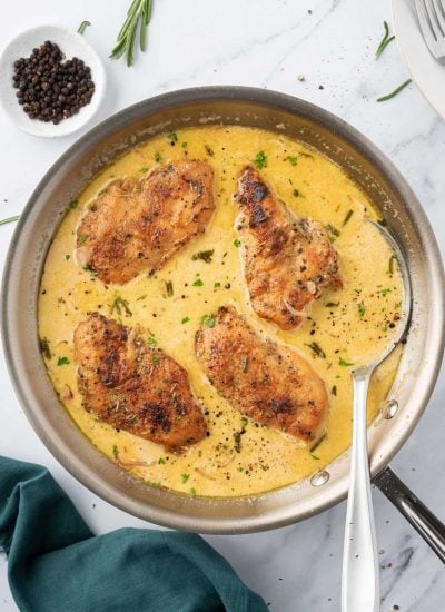 A pan of creamy mustard chicken with a spoon.