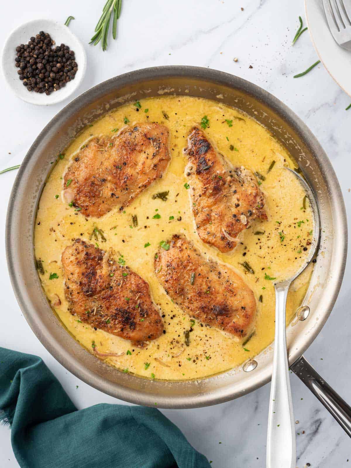 A pan of creamy mustard chicken with a spoon.