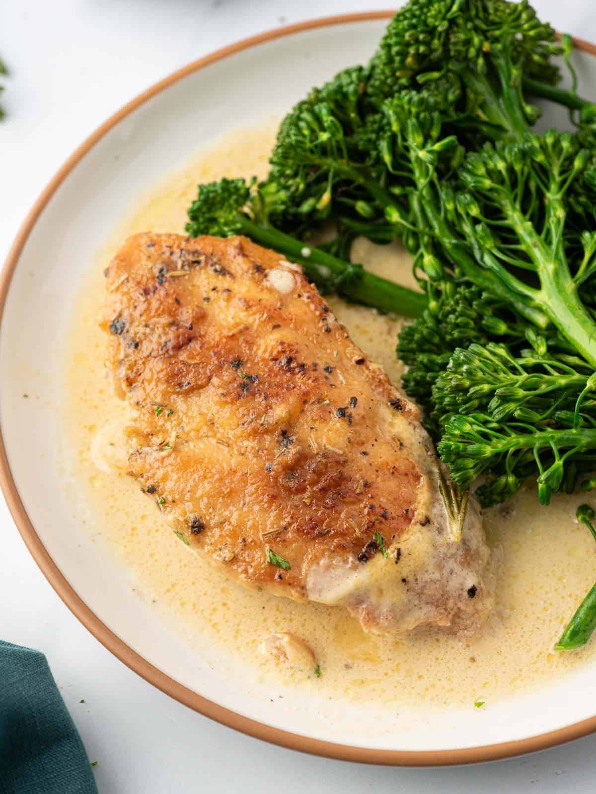 A plate of creamy mustard chicken with broccolini. 
