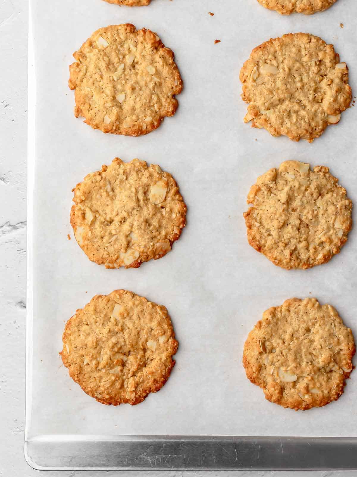 crispy almond oatmeal cookie on a baking sheet after baking.