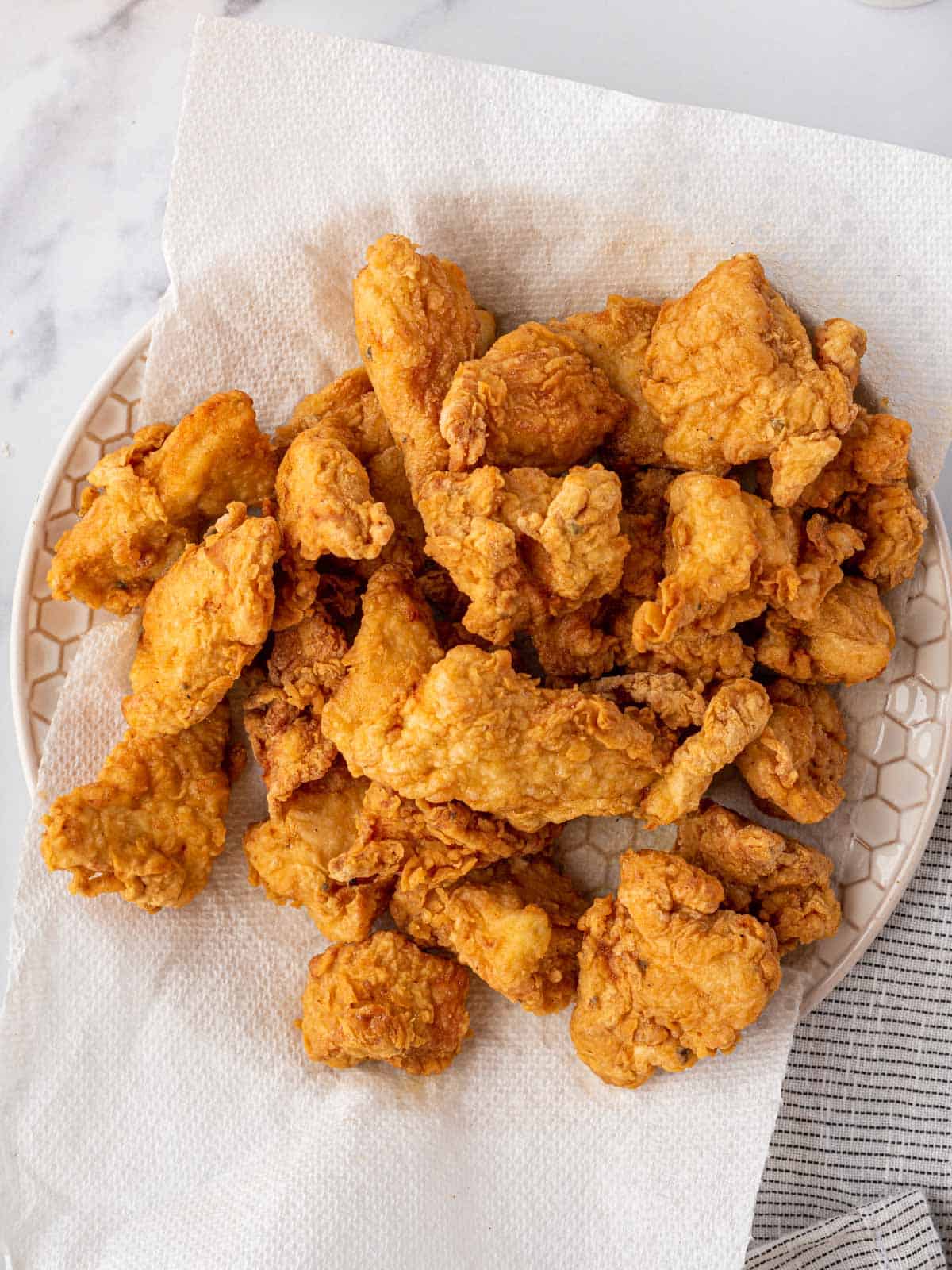 Crispy fried chicken draining on a paper towel.