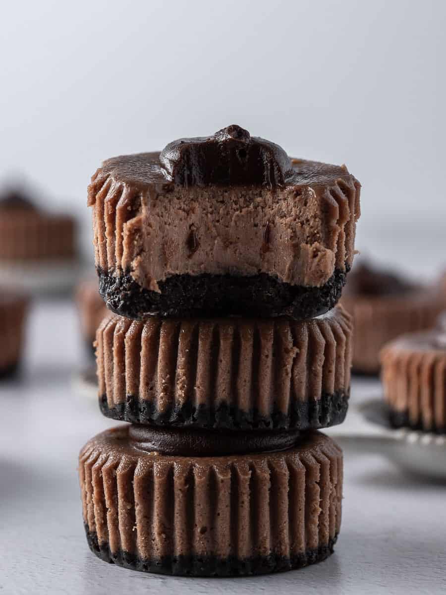 3 mini chocolate cheesecakes stacked on top of each other with a bite out of one