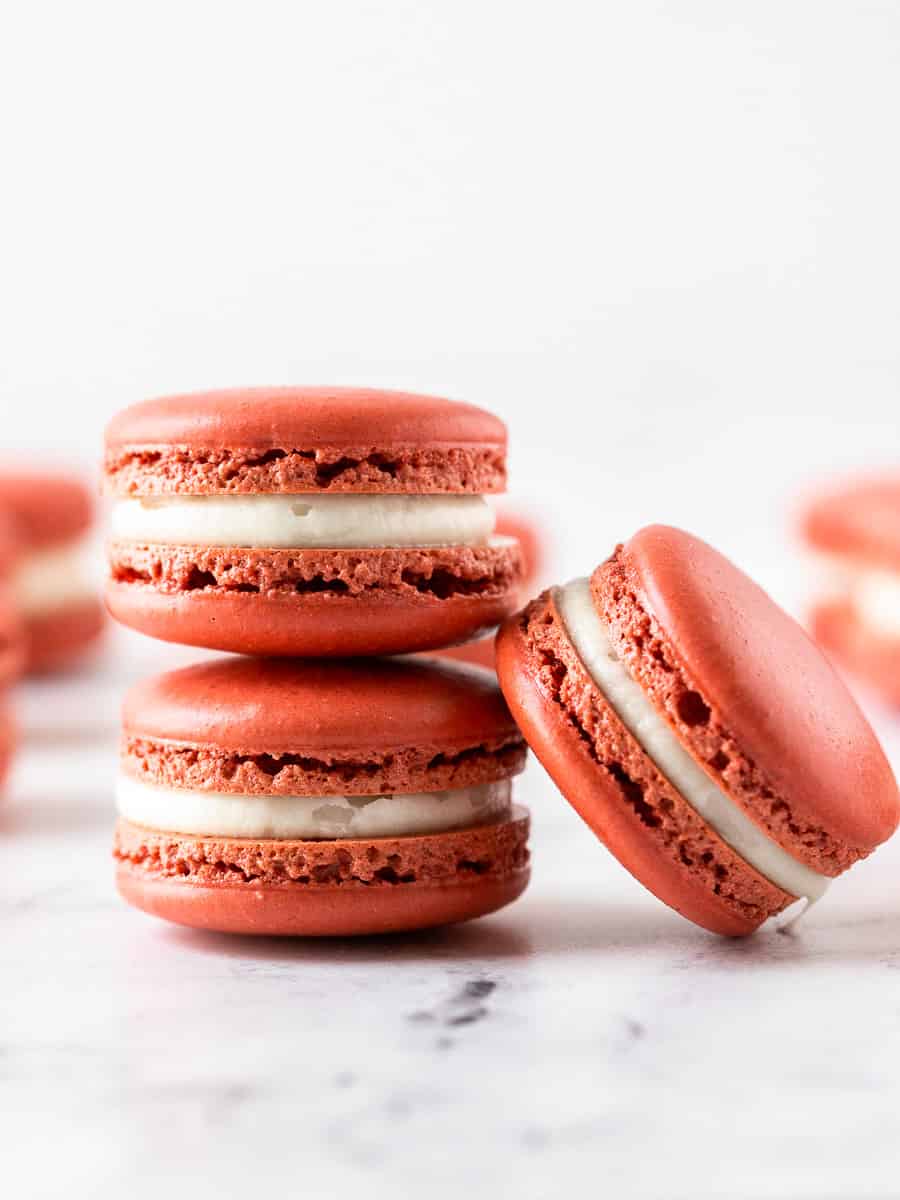 2 red velvet macarons with one other leaning on the two.