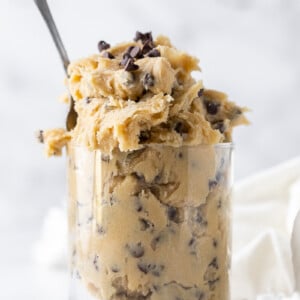 edible cookie dough in a clear glass with a spoon inside