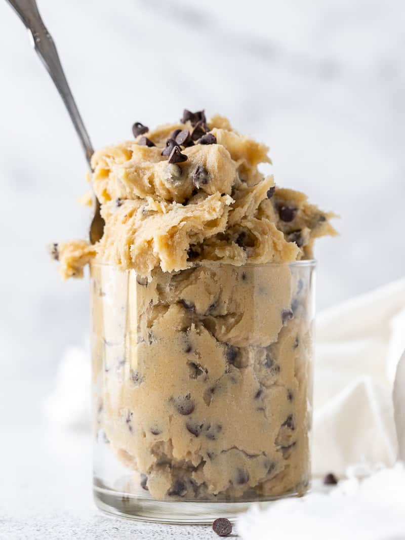 edible cookie dough in a clear glass with a spoon inside