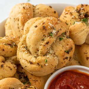 A plate of garlic knots with one in focus.