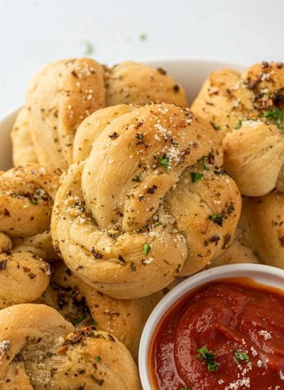 A plate of garlic knots with one in focus.