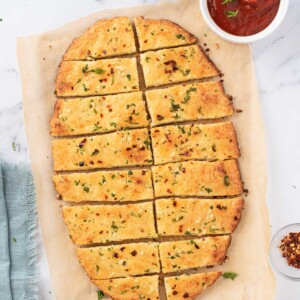 Overhead view of low carb garlic bread cut into rectangular slices with marinara on the side.