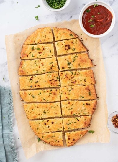 Overhead view of low carb garlic bread cut into rectangular slices with marinara on the side.