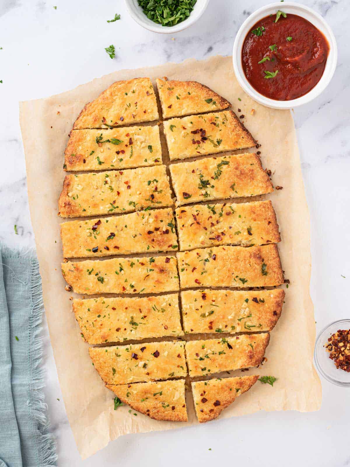 Overhead view of low carb garlic bread cut into rectangular slices with marinara on the side.